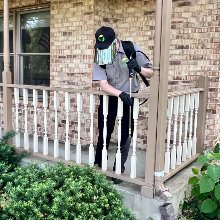 Technician treating around a front porch and its entry points