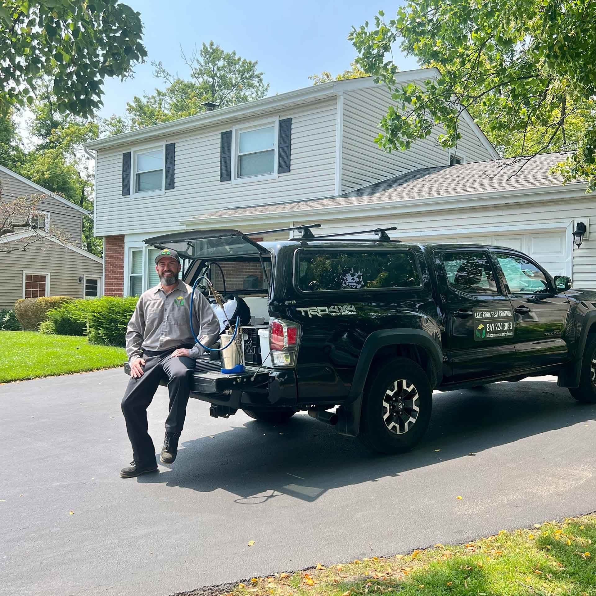 Lake Cook Pest Control technician with the company truck outside a suburban home